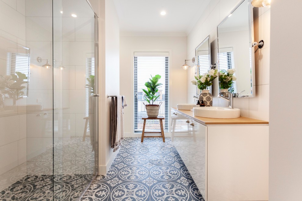 Photo of a mid-sized transitional bathroom in Melbourne with flat-panel cabinets, white cabinets, an alcove shower, white tile, ceramic tile, white walls, a vessel sink, wood benchtops, multi-coloured floor, a hinged shower door and brown benchtops.