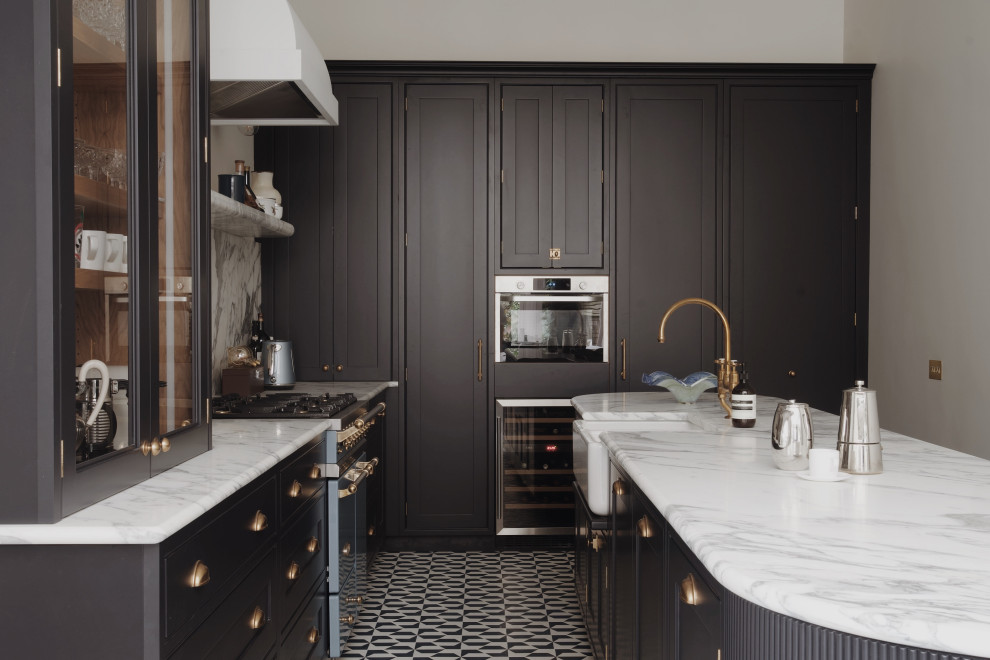 This is an example of a medium sized classic galley kitchen/diner in London with a belfast sink, shaker cabinets, black cabinets, marble worktops, white splashback, marble splashback, black appliances, porcelain flooring, an island, blue floors, white worktops, a vaulted ceiling and feature lighting.