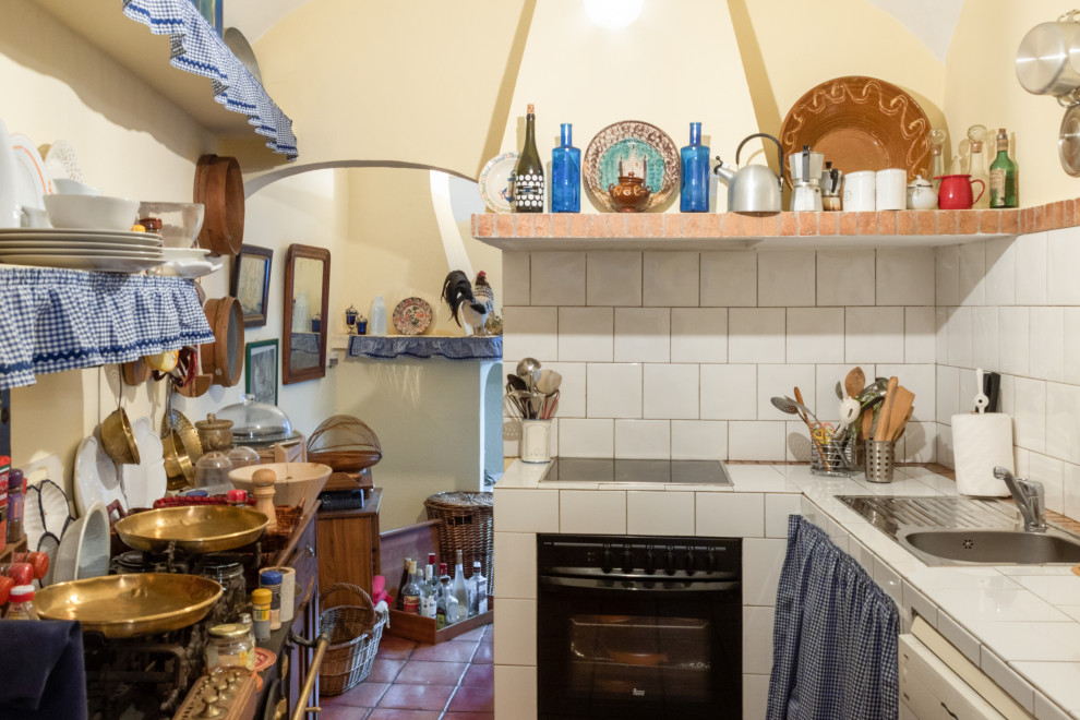 This is an example of a small country l-shaped eat-in kitchen in Other with tile benchtops, ceramic floors, white benchtop and vaulted.