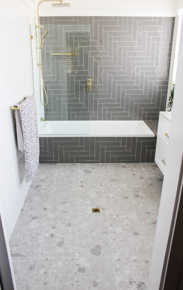 This is an example of a mid-sized modern master bathroom in Perth with shaker cabinets, white cabinets, a drop-in tub, a shower/bathtub combo, a one-piece toilet, gray tile, ceramic tile, white walls, porcelain floors, a vessel sink, engineered quartz benchtops, grey floor, a hinged shower door, white benchtops, a single vanity and a floating vanity.