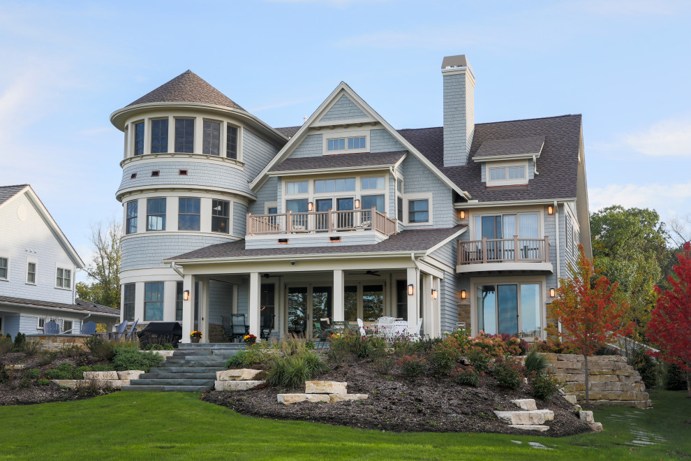 This is an example of a large beach style three-storey blue house exterior in Milwaukee with wood siding and a shingle roof.