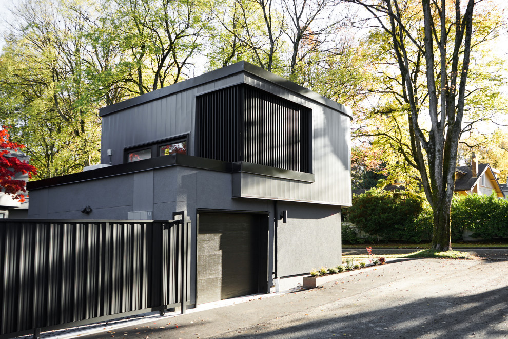 Photo of a small two-storey black exterior in Vancouver with metal siding, a flat roof, a metal roof and a black roof.