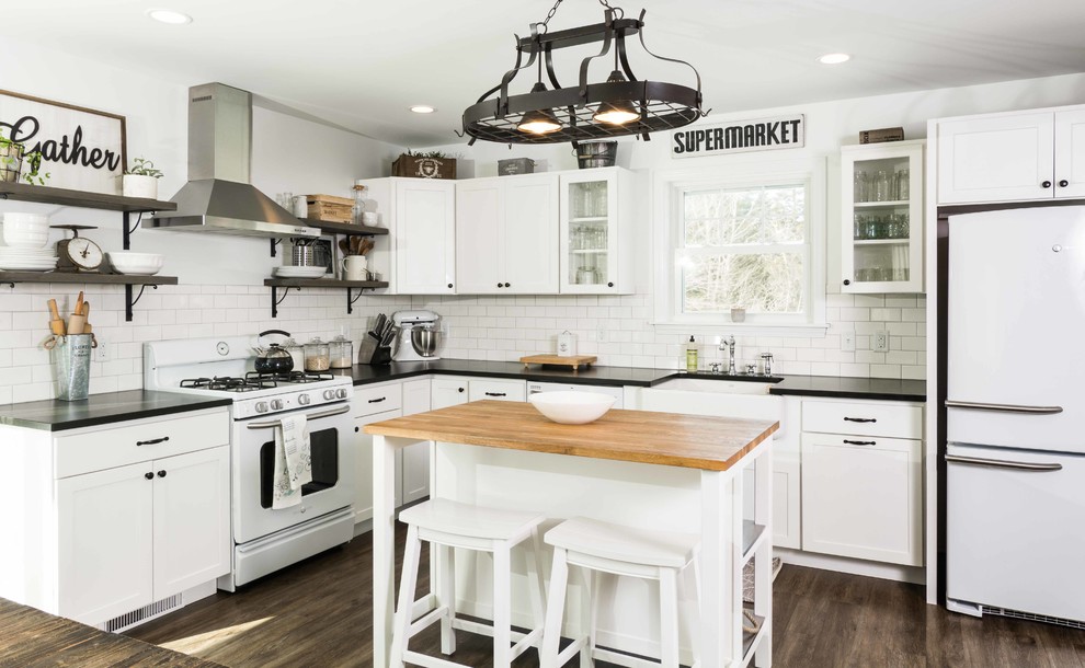 Inspiration for a mid-sized country l-shaped kitchen in Portland Maine with a farmhouse sink, shaker cabinets, white cabinets, granite benchtops, white splashback, subway tile splashback, white appliances, vinyl floors, with island and brown floor.