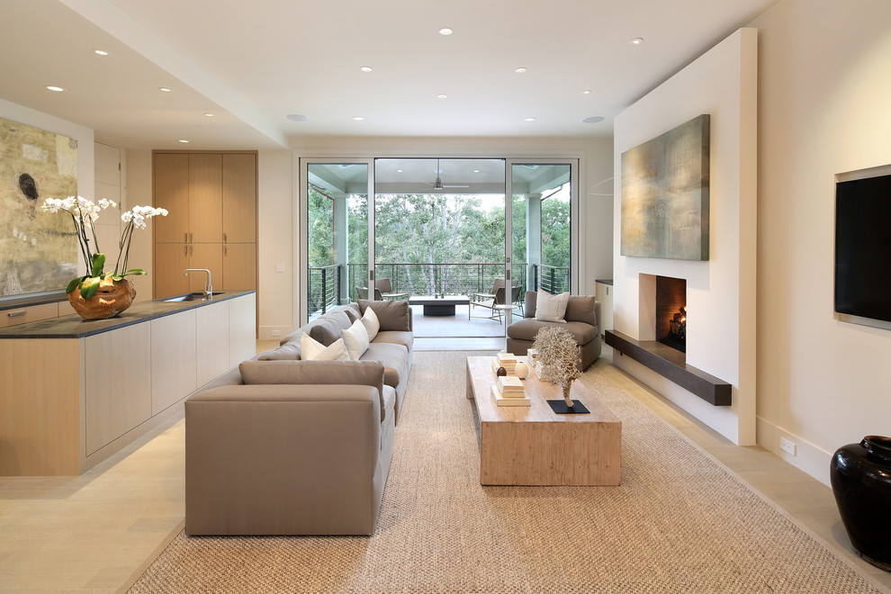 Photo of a large modern open concept family room in San Francisco with a home bar, light hardwood floors, a standard fireplace, a wall-mounted tv and white walls.