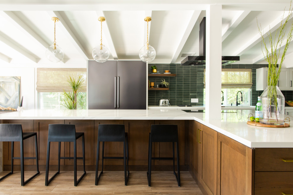 Photo of a large midcentury kitchen in Los Angeles with white cabinets, green splashback, ceramic splashback, with island, white benchtop, an undermount sink, shaker cabinets, stainless steel appliances and brown floor.