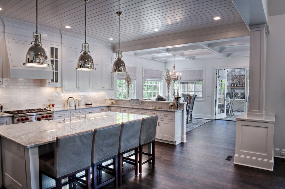 This is an example of a mid-sized traditional l-shaped eat-in kitchen in Other with shaker cabinets, white cabinets, white splashback, subway tile splashback, a farmhouse sink, stainless steel appliances and dark hardwood floors.