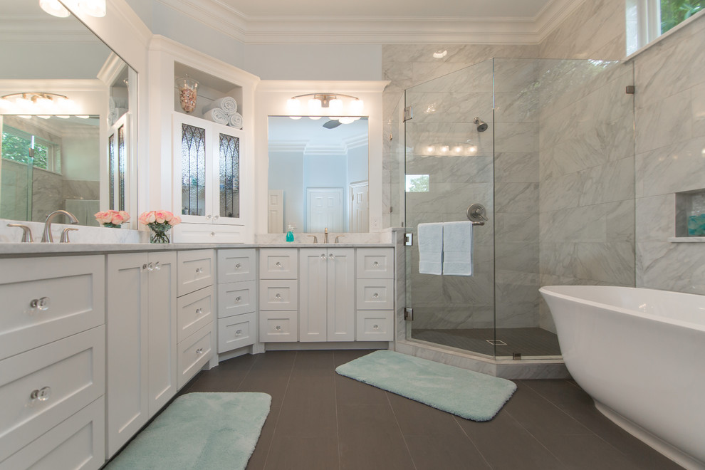 Inspiration for a large transitional master bathroom in Dallas with white cabinets, a corner shower, an undermount sink, shaker cabinets, a freestanding tub, gray tile, marble, white walls, porcelain floors, marble benchtops, grey floor, a hinged shower door and white benchtops.