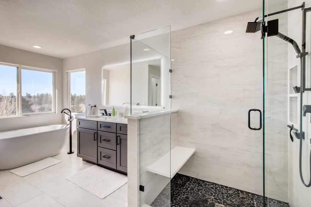 Inspiration for a medium sized modern ensuite bathroom in Denver with recessed-panel cabinets, black cabinets, a freestanding bath, an alcove shower, white tiles, white walls, white floors, a hinged door, white worktops, a shower bench, double sinks and a built in vanity unit.
