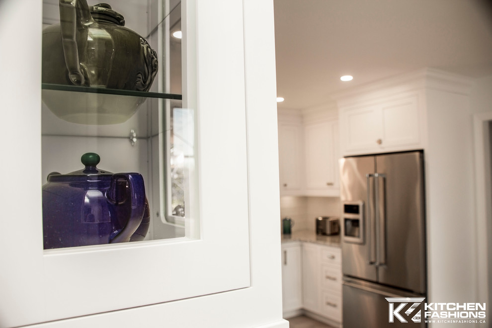 Large transitional u-shaped light wood floor eat-in kitchen photo with a farmhouse sink, shaker cabinets, white cabinets, granite countertops, white backsplash, subway tile backsplash, stainless steel appliances and no island