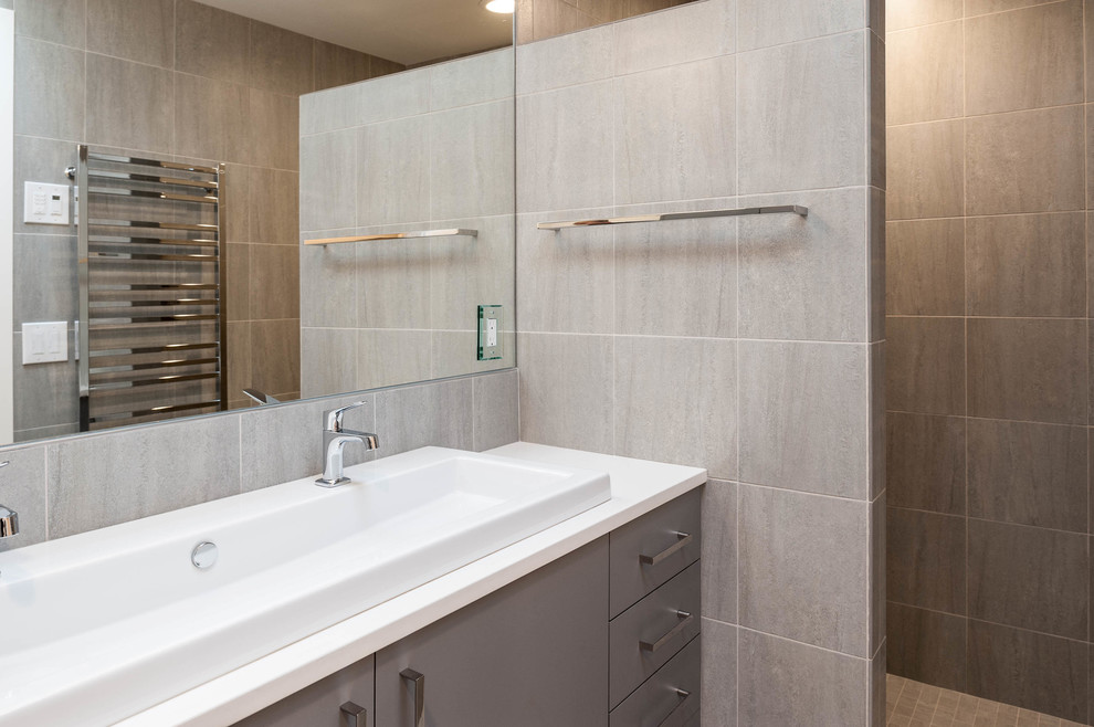 Mid-sized contemporary master bathroom in Seattle with a vessel sink, flat-panel cabinets, grey cabinets, solid surface benchtops, a japanese tub, an open shower, a one-piece toilet, gray tile, stone tile, grey walls and porcelain floors.