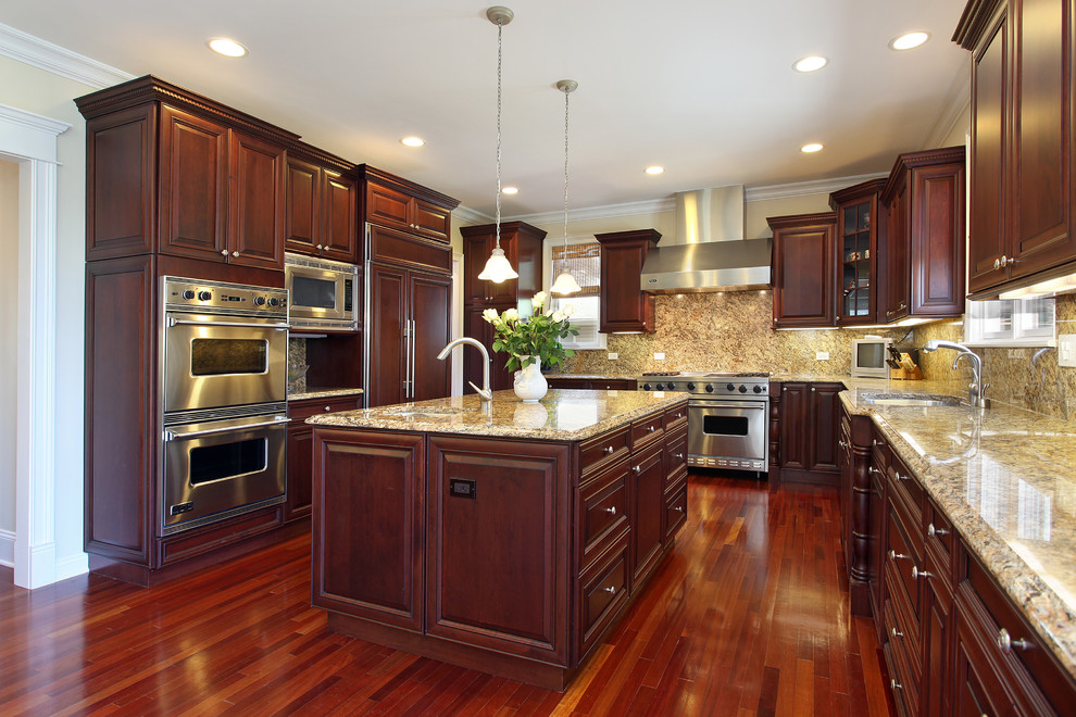 Photo of a mid-sized traditional u-shaped separate kitchen in Houston with a single-bowl sink, raised-panel cabinets, dark wood cabinets, granite benchtops, brown splashback, stone slab splashback, panelled appliances, dark hardwood floors, with island, brown floor and brown benchtop.
