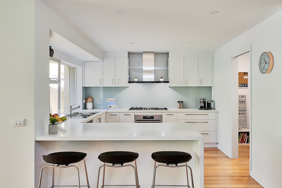 Photo of a mid-sized contemporary kitchen in Melbourne with a double-bowl sink, flat-panel cabinets, white cabinets and a peninsula.