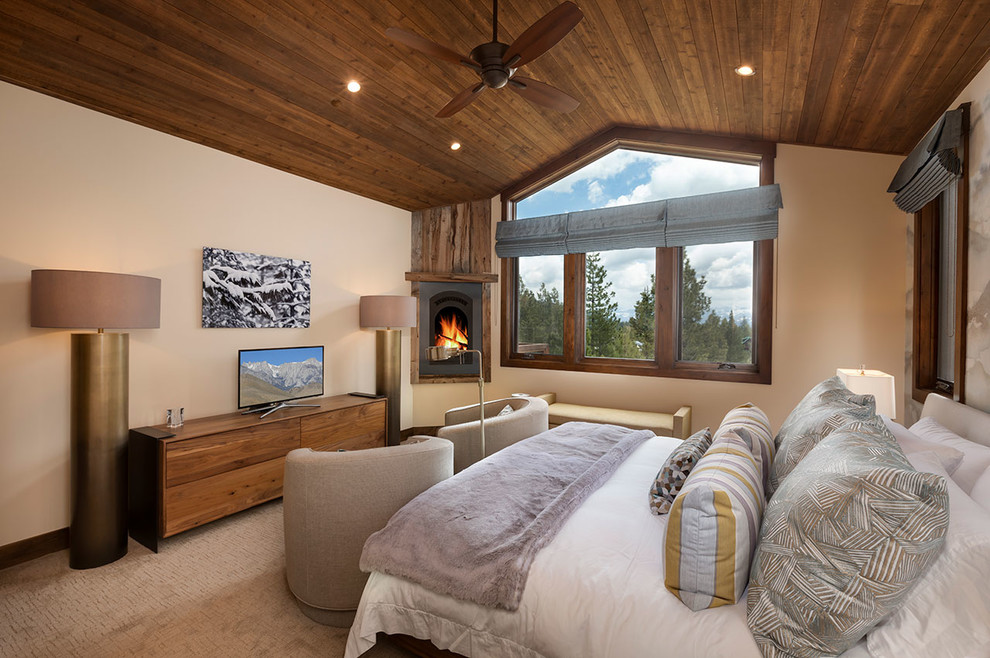 Inspiration for a mid-sized rustic master carpeted and brown floor bedroom remodel with beige walls, a corner fireplace and a wood fireplace surround