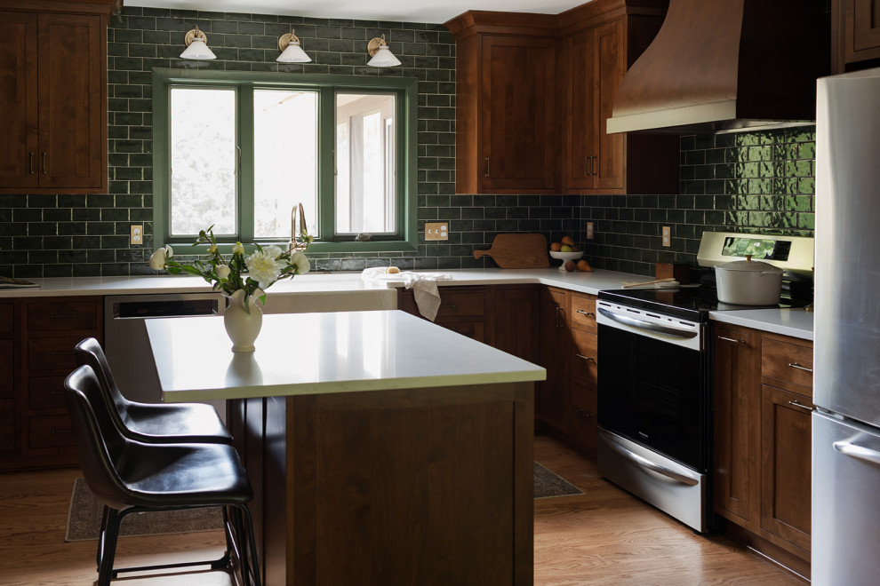 Inspiration for a mid-sized transitional l-shaped medium tone wood floor and brown floor kitchen pantry remodel with a farmhouse sink, shaker cabinets, medium tone wood cabinets, quartz countertops, green backsplash, subway tile backsplash, stainless steel appliances, an island and white countertops