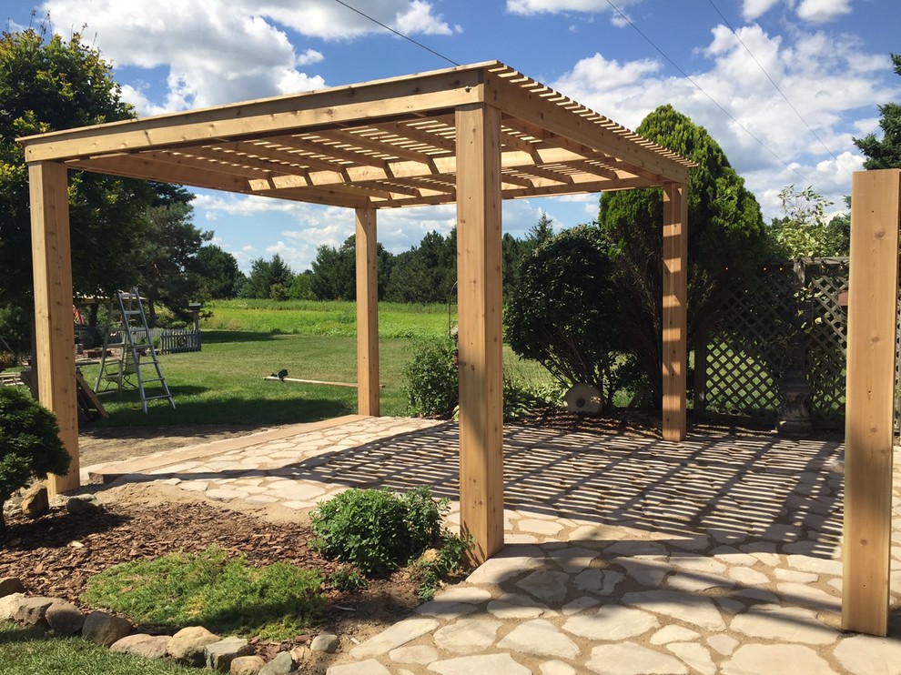 Photo of a mid-sized transitional backyard patio in Detroit with a pergola, a vegetable garden and natural stone pavers.