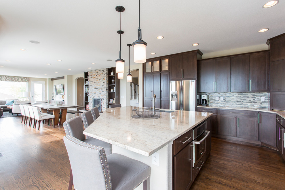 Example of a large transitional l-shaped dark wood floor and brown floor open concept kitchen design in Denver with an undermount sink, shaker cabinets, dark wood cabinets, granite countertops, metallic backsplash, glass tile backsplash, stainless steel appliances and an island