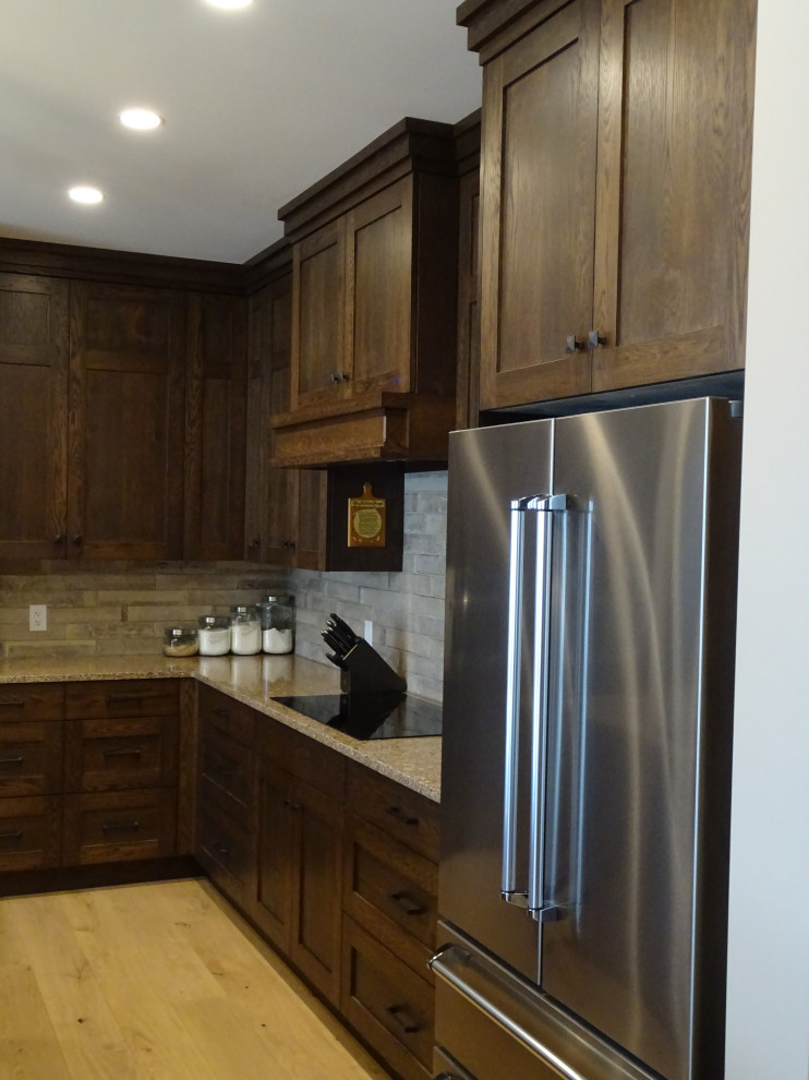 Kitchen pantry - large transitional l-shaped light wood floor and brown floor kitchen pantry idea with an undermount sink, shaker cabinets, medium tone wood cabinets, granite countertops, gray backsplash, subway tile backsplash, stainless steel appliances, an island and multicolored countertops