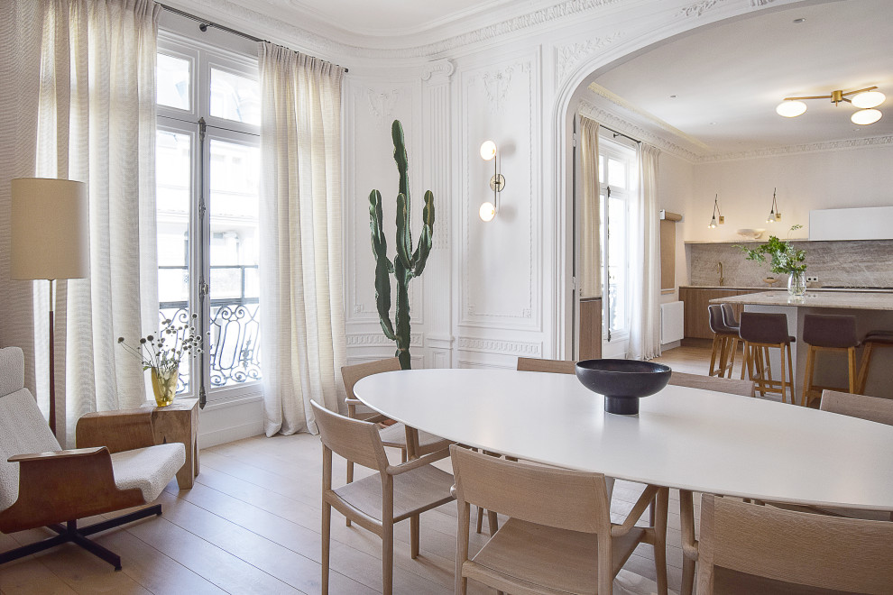 Large contemporary open plan dining in Paris with white walls, light hardwood floors and decorative wall panelling.