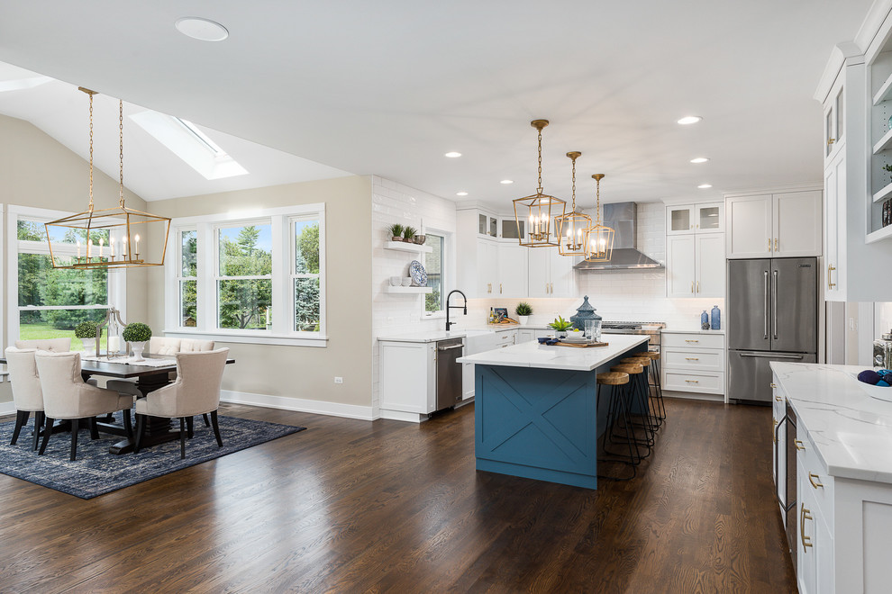 Large transitional l-shaped dark wood floor and brown floor open concept kitchen photo in Chicago with a farmhouse sink, shaker cabinets, white cabinets, quartzite countertops, white backsplash, subway tile backsplash, stainless steel appliances, an island and white countertops