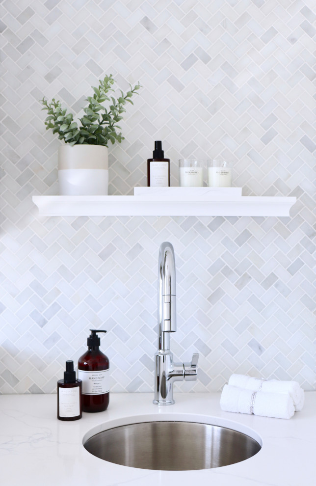 Bild på en mellanstor funkis vita parallell vitt tvättstuga, med en enkel diskho, släta luckor, grå skåp, bänkskiva i kvarts, stänkskydd i marmor, grå väggar och en tvättmaskin och torktumlare bredvid varandra