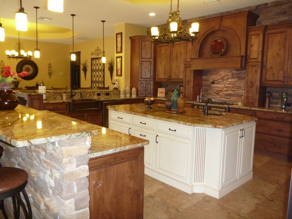 Photo of a mid-sized mediterranean u-shaped eat-in kitchen in Tampa with a farmhouse sink, raised-panel cabinets, distressed cabinets, granite benchtops, multi-coloured splashback, stone slab splashback, stainless steel appliances, porcelain floors and multiple islands.