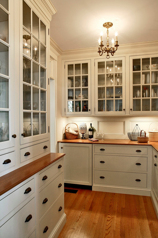 Example of a large transitional l-shaped medium tone wood floor and brown floor kitchen design in Boston with glass-front cabinets, white cabinets, wood countertops, white backsplash and wood backsplash