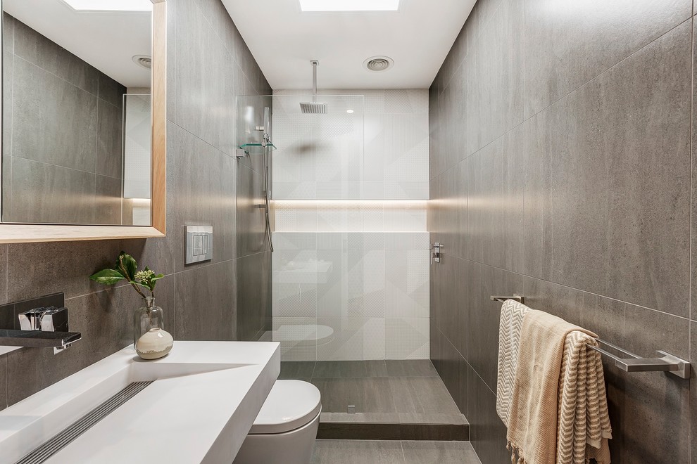 Photo of a contemporary 3/4 bathroom in Melbourne with an alcove shower, a one-piece toilet, gray tile, white tile, a wall-mount sink, grey floor, an open shower and white benchtops.