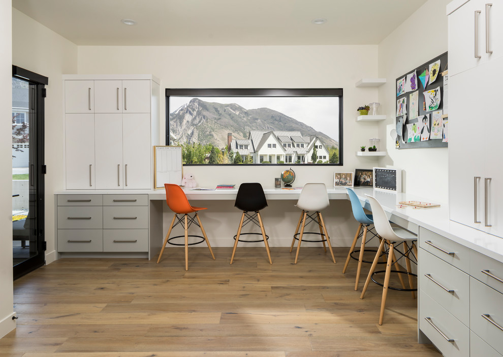 Photo of an expansive contemporary study room in Salt Lake City with white walls, light hardwood floors, a built-in desk and beige floor.