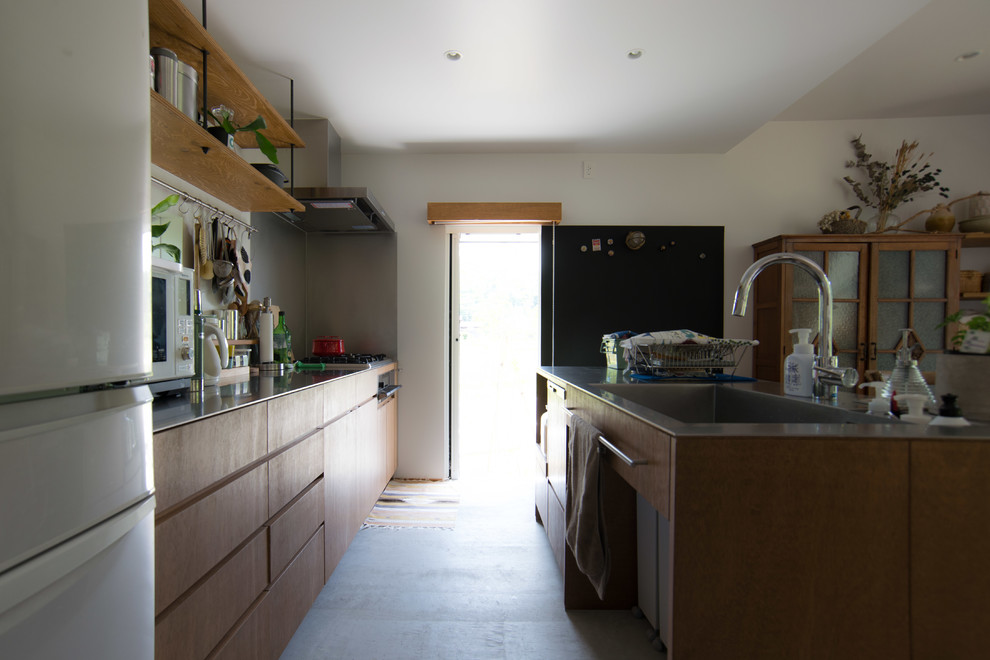This is an example of a mid-sized traditional single-wall eat-in kitchen in Other with an undermount sink, stainless steel benchtops, concrete floors, with island, grey floor and flat-panel cabinets.