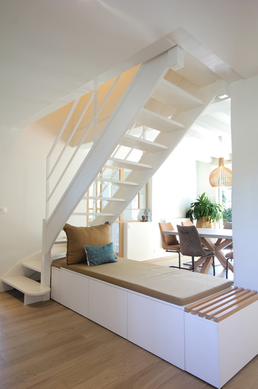 Diseño de escalera curva escandinava de tamaño medio sin contrahuella con escalones de madera pintada y barandilla de metal