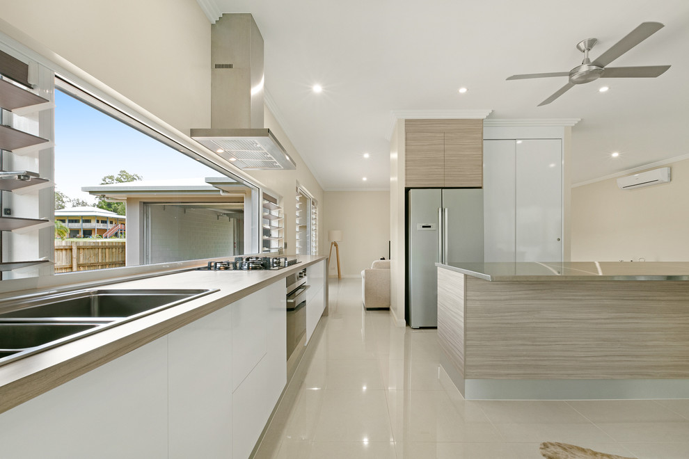 Inspiration for a large contemporary l-shaped eat-in kitchen in Cairns with an undermount sink, beige cabinets, stainless steel benchtops, black splashback, ceramic splashback, stainless steel appliances, porcelain floors and with island.