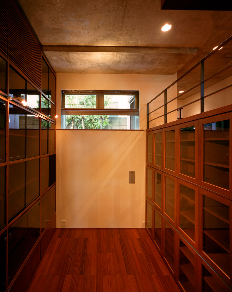 Inspiration for a small modern home office in Tokyo with a library, white walls, medium hardwood floors, no fireplace, a plaster fireplace surround, a built-in desk and brown floor.