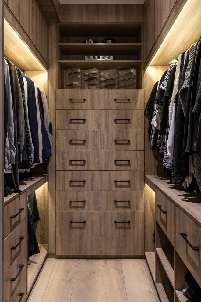 Design ideas for a mid-sized contemporary gender-neutral walk-in wardrobe in London with flat-panel cabinets, light wood cabinets, light hardwood floors and brown floor.