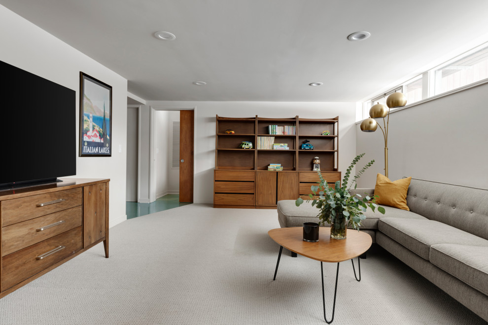Imagen de sala de estar cerrada retro de tamaño medio con paredes blancas, moqueta, televisor colgado en la pared y suelo gris