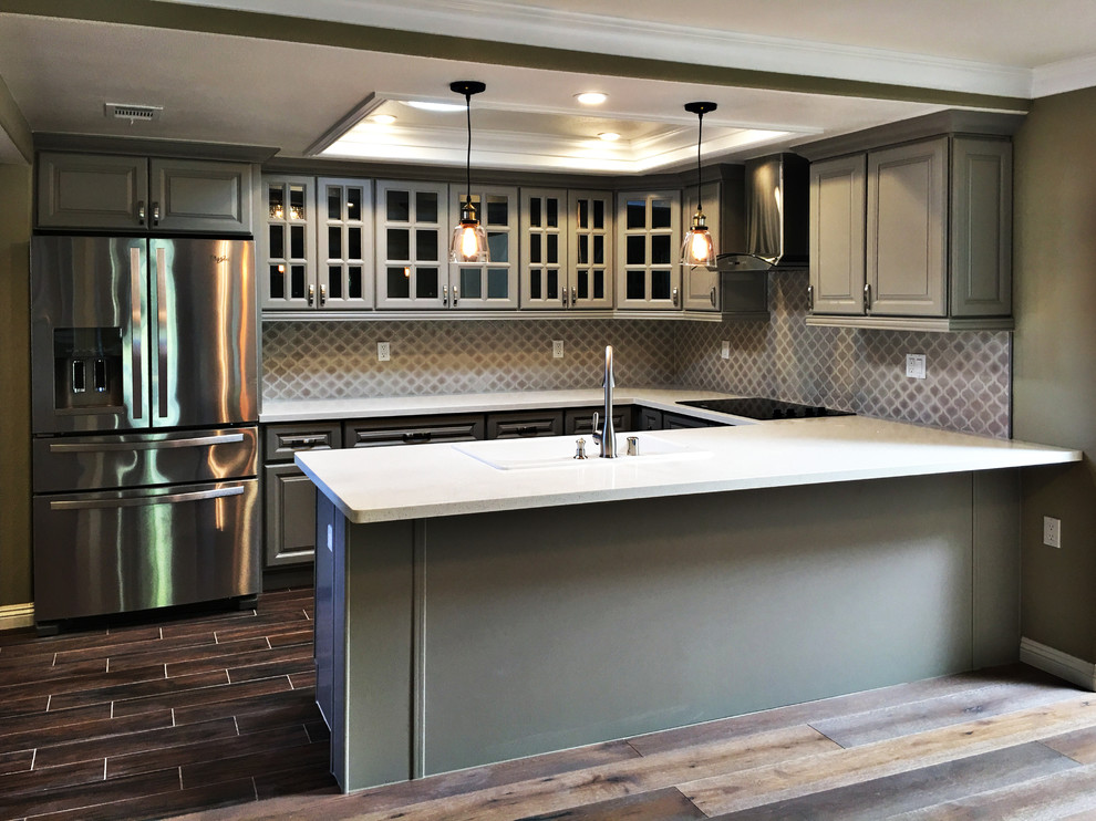 Eat-in kitchen - mid-sized transitional u-shaped medium tone wood floor eat-in kitchen idea in Orange County with raised-panel cabinets, gray cabinets, quartz countertops, a peninsula, a double-bowl sink, brown backsplash, mosaic tile backsplash and stainless steel appliances