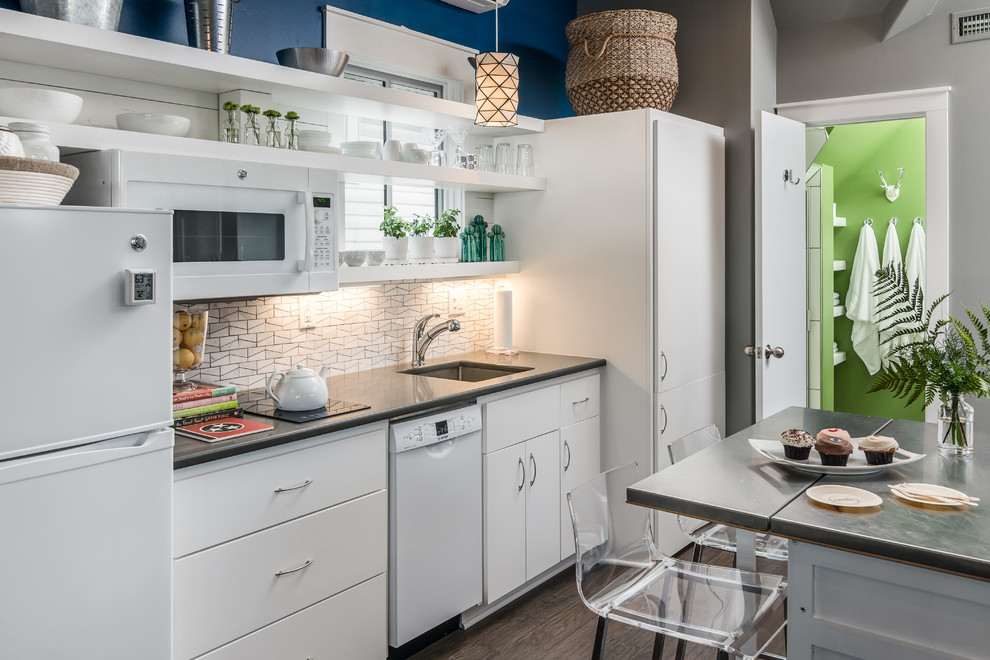 Contemporary single-wall kitchen in Nashville with a single-bowl sink, flat-panel cabinets, white cabinets, quartzite benchtops, white splashback, mosaic tile splashback, stainless steel appliances, with island and grey benchtop.