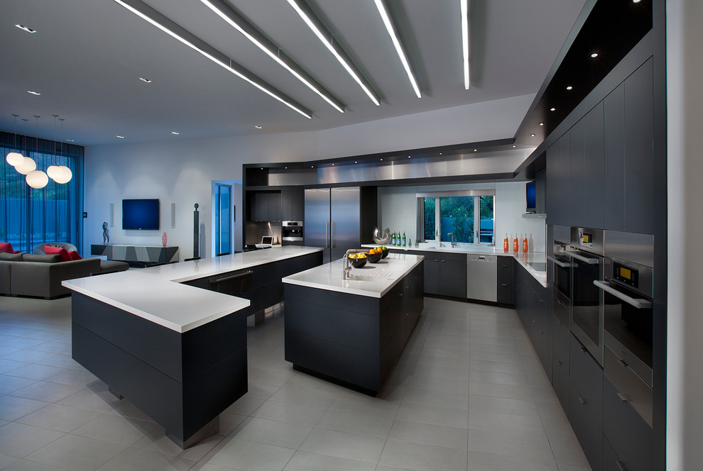 Photo of a contemporary l-shaped open plan kitchen in Phoenix with flat-panel cabinets, black cabinets, stainless steel appliances, an integrated sink, quartz benchtops, metallic splashback, glass sheet splashback, porcelain floors and multiple islands.