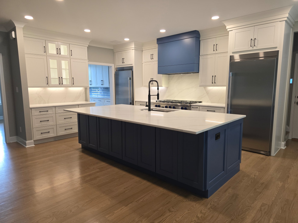 Inspiration for a large modern l-shaped medium tone wood floor and brown floor kitchen remodel with an undermount sink, shaker cabinets, white cabinets, quartz countertops, white backsplash, quartz backsplash, stainless steel appliances, an island and white countertops