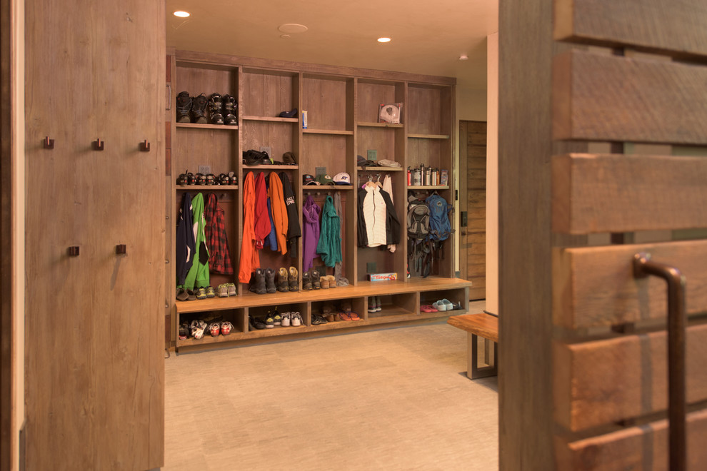 Photo of a large industrial mudroom in Other with beige walls and carpet.