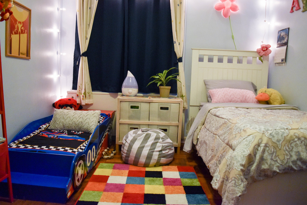 This is an example of a mid-sized traditional gender-neutral kids' bedroom for kids 4-10 years old in New York with blue walls, dark hardwood floors and brown floor.