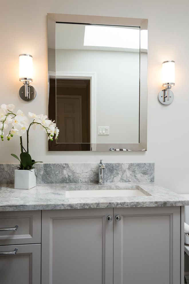 Mid-sized transitional master bathroom in Vancouver with shaker cabinets, white cabinets, an alcove tub, a shower/bathtub combo, a two-piece toilet, white tile, porcelain tile, grey walls, porcelain floors, an undermount sink and marble benchtops.