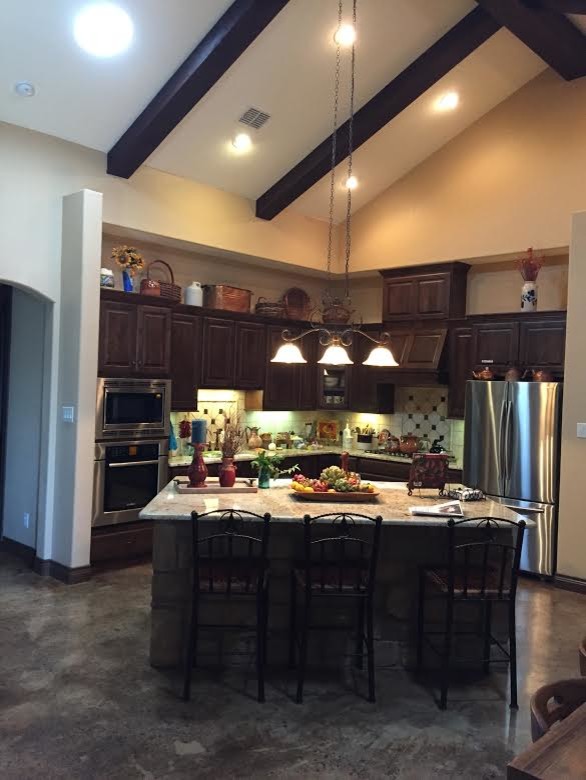 Inspiration for a mid-sized rustic l-shaped ceramic tile eat-in kitchen remodel in Austin with an undermount sink, shaker cabinets, dark wood cabinets, granite countertops, beige backsplash, ceramic backsplash, stainless steel appliances and an island