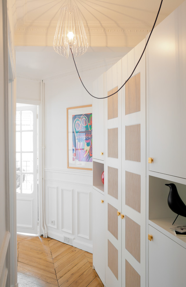 This is an example of a mid-sized contemporary entry hall in Paris with white walls and light hardwood floors.