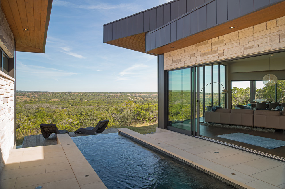 Design ideas for a mid-sized contemporary courtyard custom-shaped infinity pool in Austin with concrete pavers.