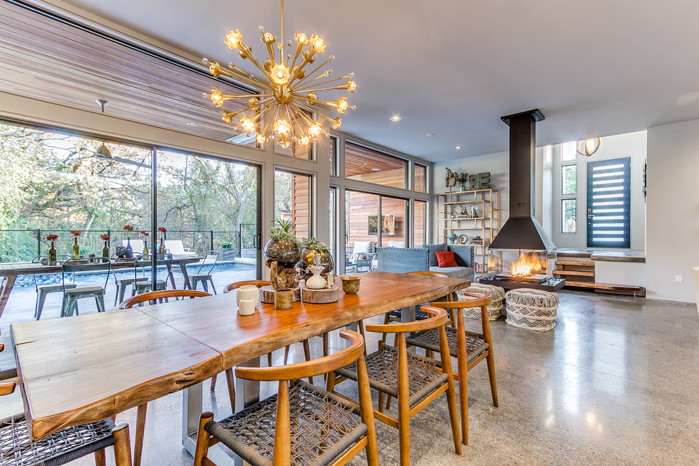 Contemporary open plan dining in Oklahoma City with white walls, concrete floors and a two-sided fireplace.