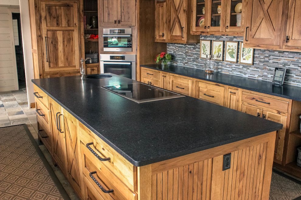 Design ideas for a mid-sized country galley eat-in kitchen in Other with granite benchtops, with island, an undermount sink, shaker cabinets, medium wood cabinets, grey splashback, matchstick tile splashback, stainless steel appliances, limestone floors and multi-coloured floor.