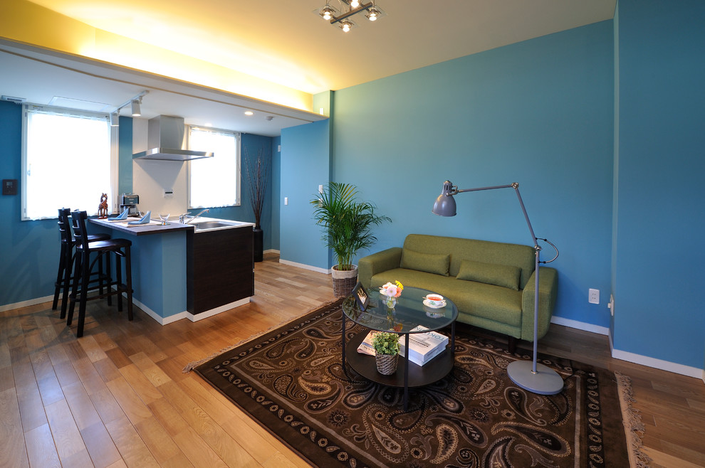 This is an example of a small transitional open concept living room in Osaka with blue walls and light hardwood floors.