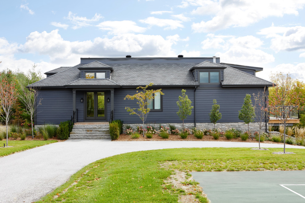 На фото: большой, синий, деревянный частный загородный дом в стиле неоклассика (современная классика) с разными уровнями, мансардной крышей, крышей из гибкой черепицы, черной крышей и отделкой планкеном