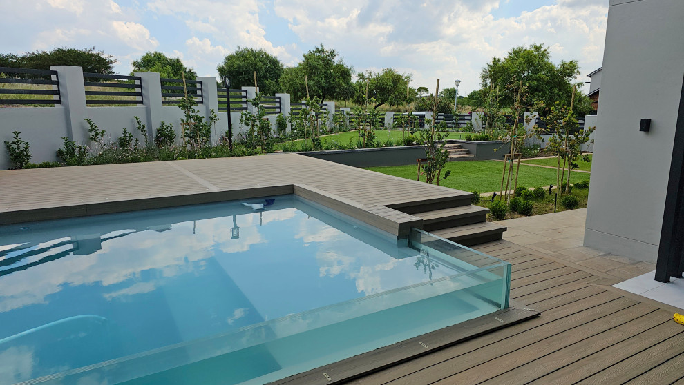 This is an example of a mid-sized contemporary side yard rectangular pool in Other with decking and with a pool.