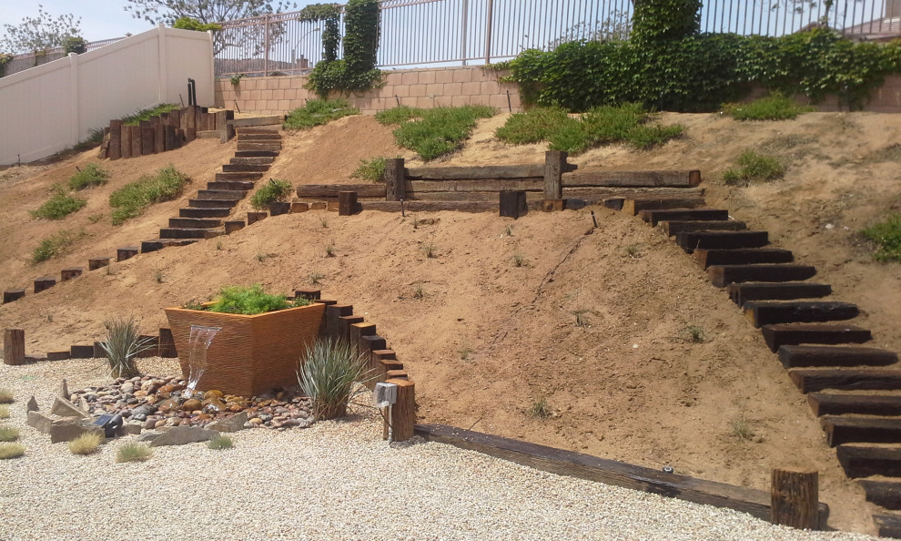 Design ideas for a mid-sized contemporary sloped full sun xeriscape for summer in Los Angeles with a water feature and river rock.